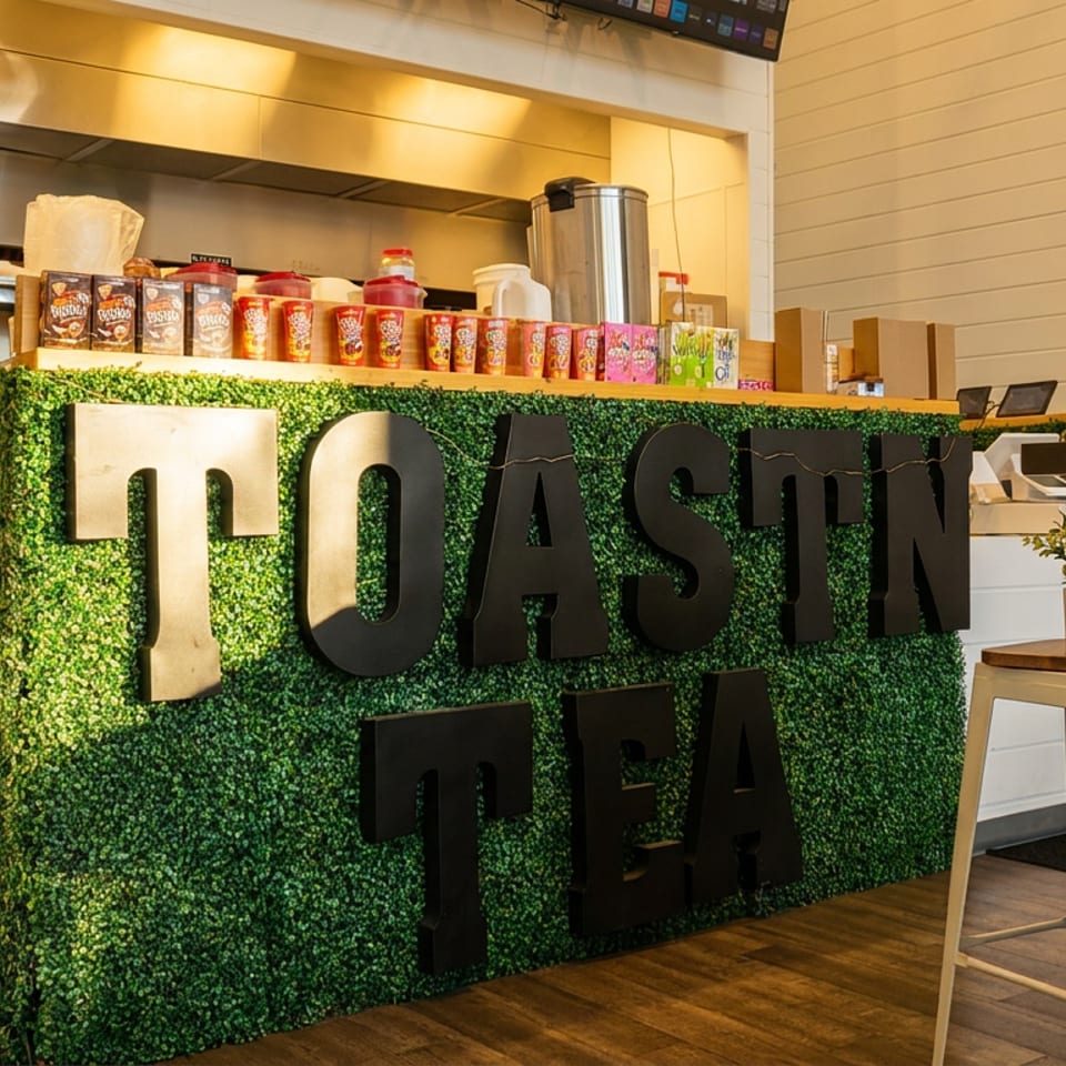 Interior of Toastin' Tea with a green hedge wall, counter, and bar stools.