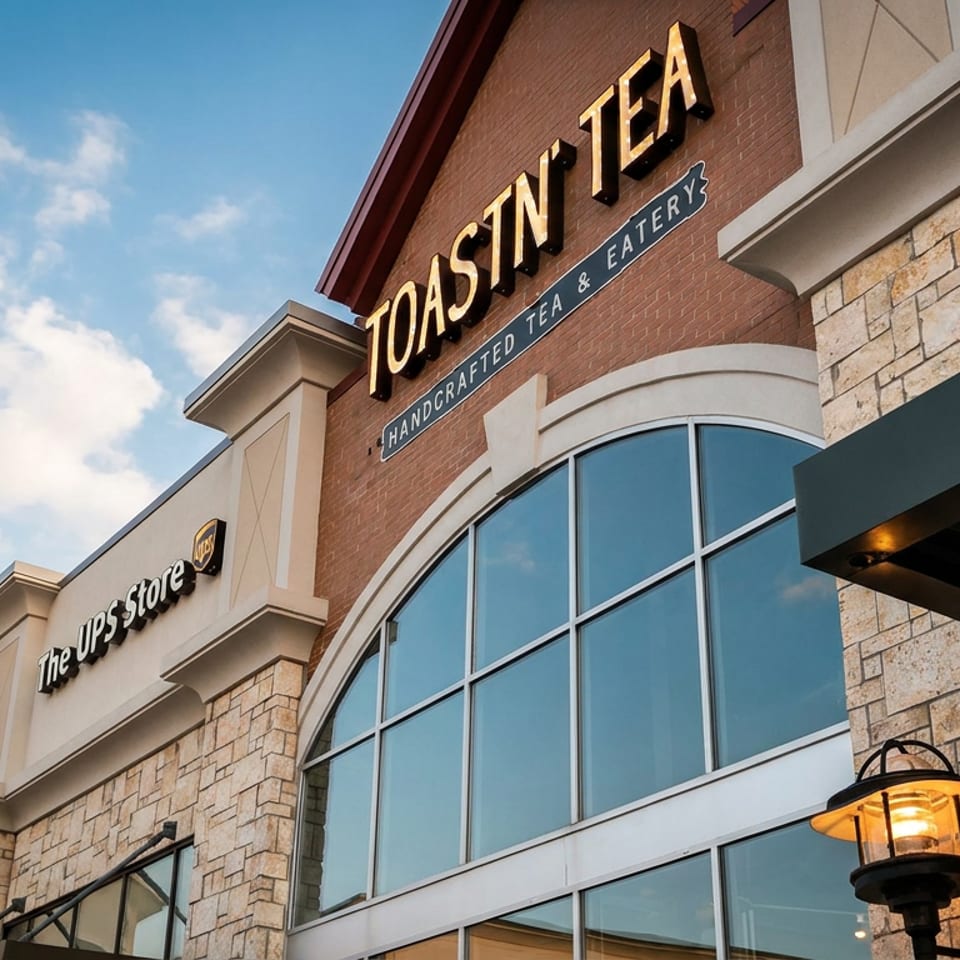 Exterior of Toastn Tea and The UPS Store in a brick and stone building under a blue sky.